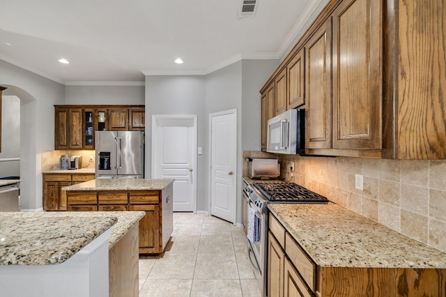 kitchen featuring light tile patterned floors, tasteful backsplash, visible vents, arched walkways, and stainless steel appliances