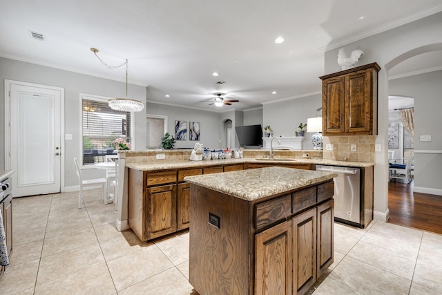 kitchen featuring arched walkways, stainless steel dishwasher, light tile patterned floors, and a sink