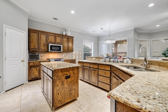 kitchen featuring light tile patterned floors, a kitchen island, a sink, visible vents, and appliances with stainless steel finishes