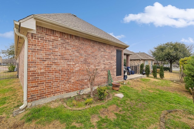 view of home's exterior with brick siding, fence, and a lawn