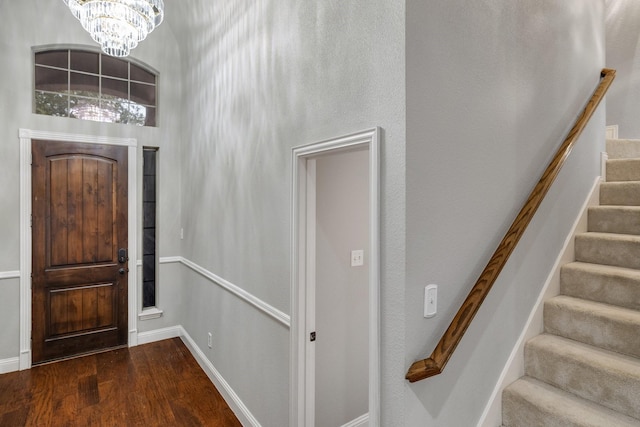 entrance foyer featuring a chandelier, stairway, wood finished floors, and baseboards