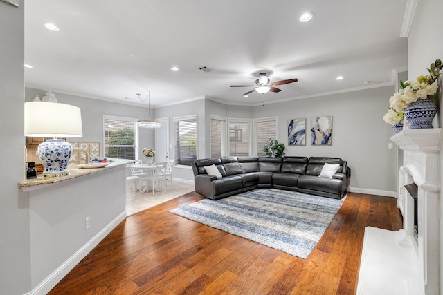 living room featuring a premium fireplace, wood finished floors, visible vents, baseboards, and crown molding