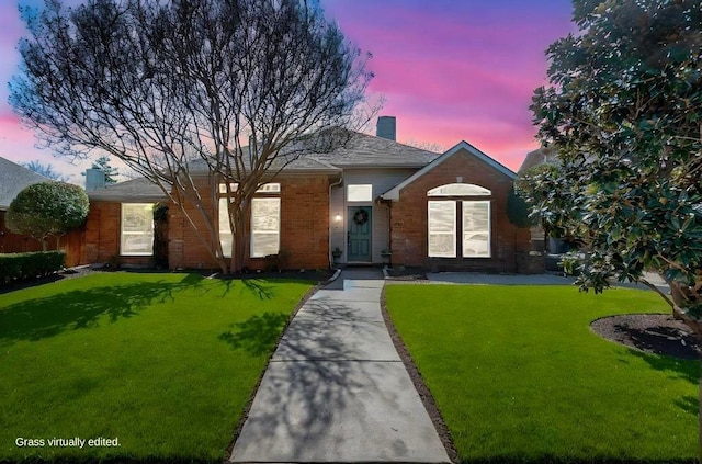 single story home with brick siding, a chimney, and a yard