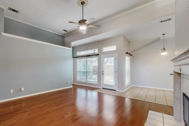 unfurnished living room featuring ceiling fan, light wood finished floors, a tiled fireplace, and visible vents