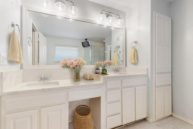 bathroom featuring double vanity, a stall shower, a sink, and baseboards