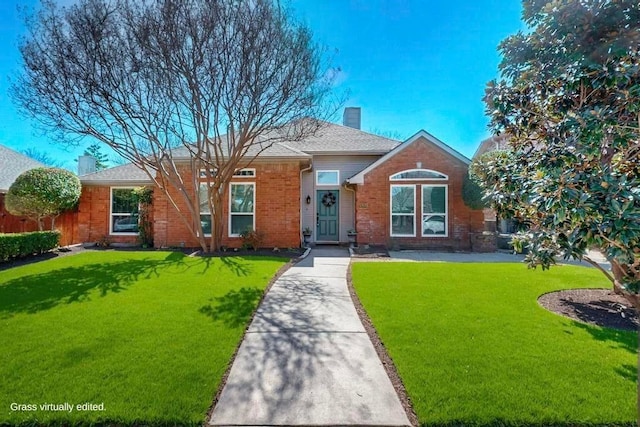 view of front of property featuring brick siding, a chimney, and a front yard