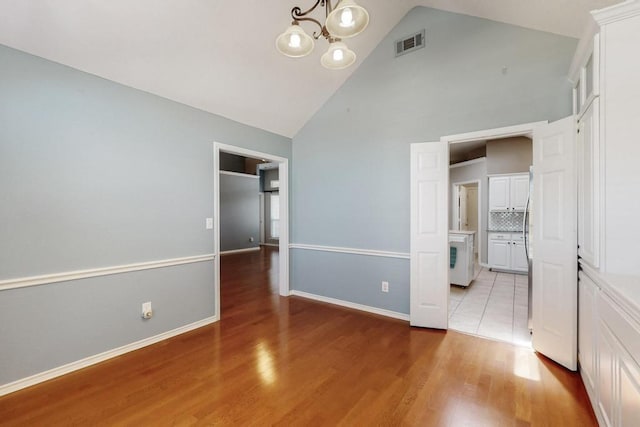 unfurnished bedroom featuring baseboards, wood finished floors, visible vents, and an inviting chandelier