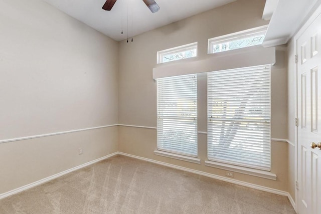 carpeted empty room featuring baseboards and a ceiling fan