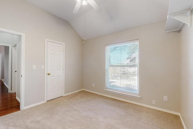 spare room with vaulted ceiling, ceiling fan, light carpet, and baseboards