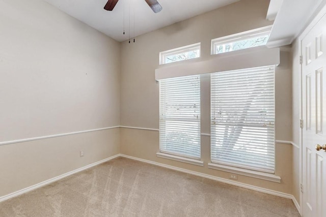 carpeted empty room featuring ceiling fan and baseboards