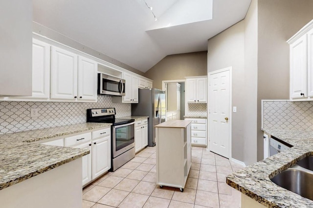 kitchen with light tile patterned floors, light stone counters, stainless steel appliances, white cabinets, and vaulted ceiling