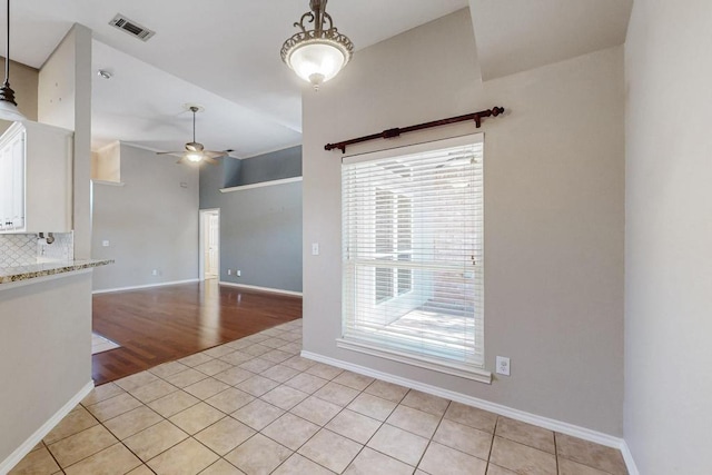 spare room with a ceiling fan, visible vents, baseboards, and light tile patterned flooring