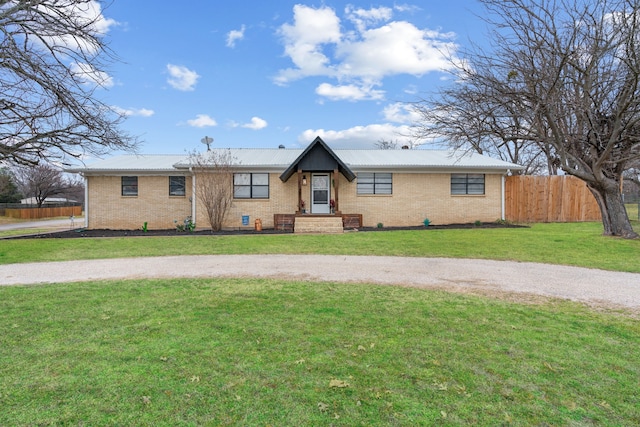 single story home featuring metal roof, a front lawn, fence, and brick siding