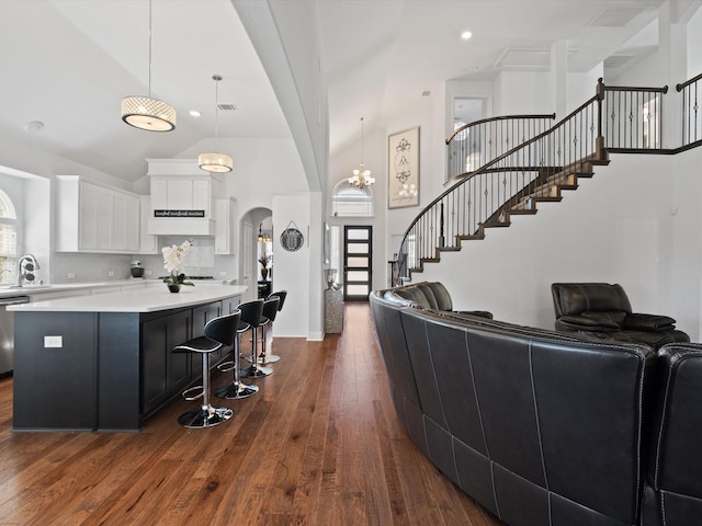 kitchen with open floor plan, dark wood-style flooring, arched walkways, and a sink