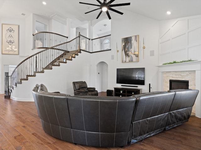 living area with high vaulted ceiling, recessed lighting, a fireplace, wood finished floors, and stairs