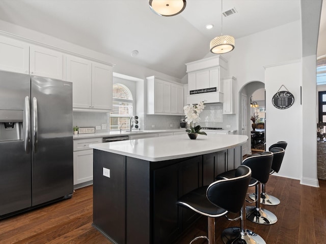 kitchen with arched walkways, a breakfast bar, stainless steel appliances, white cabinetry, and a sink