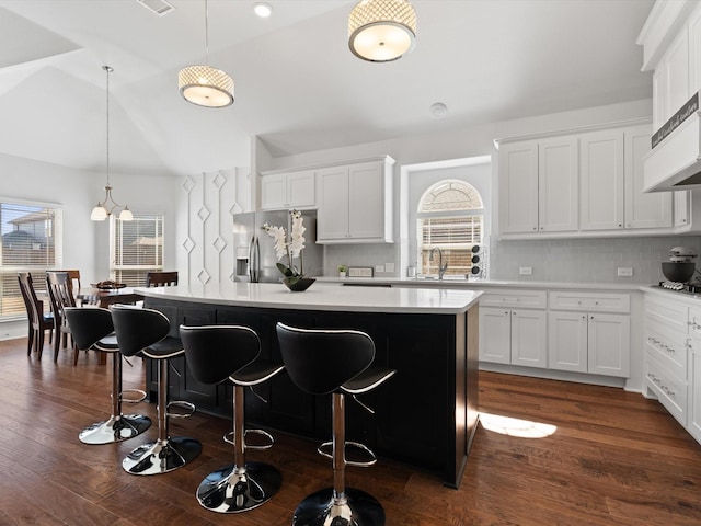 kitchen featuring tasteful backsplash, lofted ceiling, a kitchen island, a breakfast bar, and stainless steel appliances