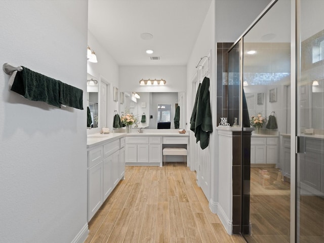 full bathroom with visible vents, tiled shower, wood finished floors, and vanity