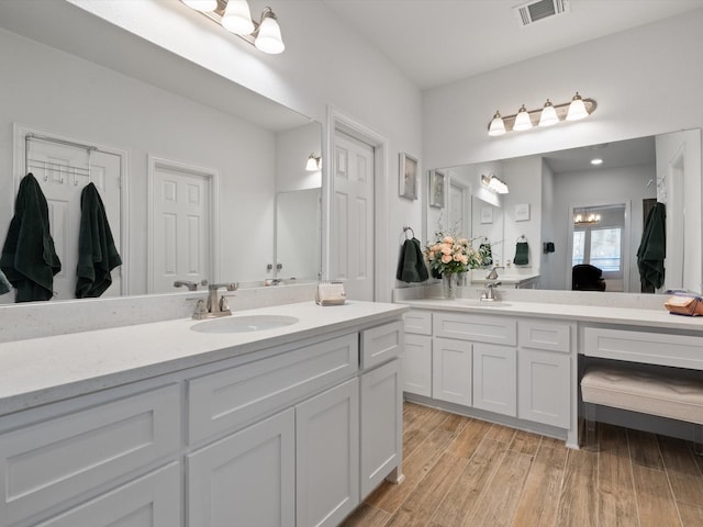 ensuite bathroom featuring vanity, ensuite bath, wood finished floors, and visible vents