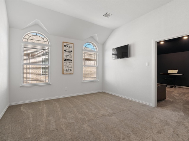 carpeted empty room featuring baseboards, visible vents, and vaulted ceiling