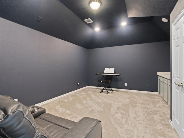 home theater room featuring light carpet, visible vents, and vaulted ceiling