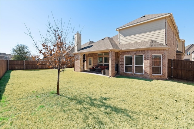 back of property with a fenced backyard, brick siding, a shingled roof, a lawn, and a patio area