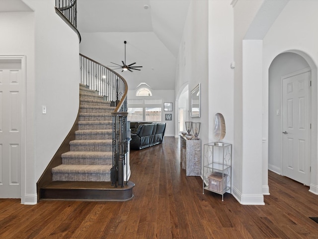 entrance foyer featuring baseboards, a ceiling fan, wood finished floors, stairs, and high vaulted ceiling