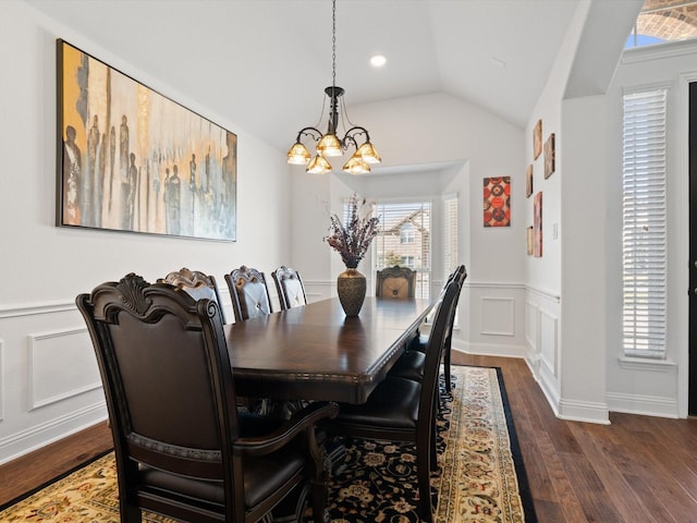 dining room featuring lofted ceiling, a wainscoted wall, dark wood-type flooring, a chandelier, and a decorative wall