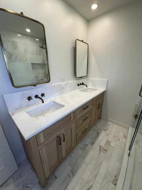 full bath featuring double vanity, a sink, and a marble finish shower