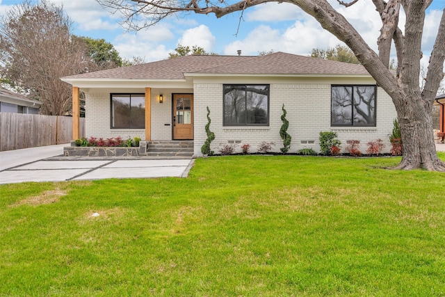 view of front of home with brick siding, fence, roof with shingles, crawl space, and a front lawn