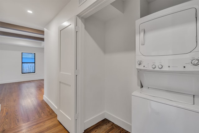 laundry room featuring laundry area, stacked washer / dryer, wood-type flooring, and baseboards