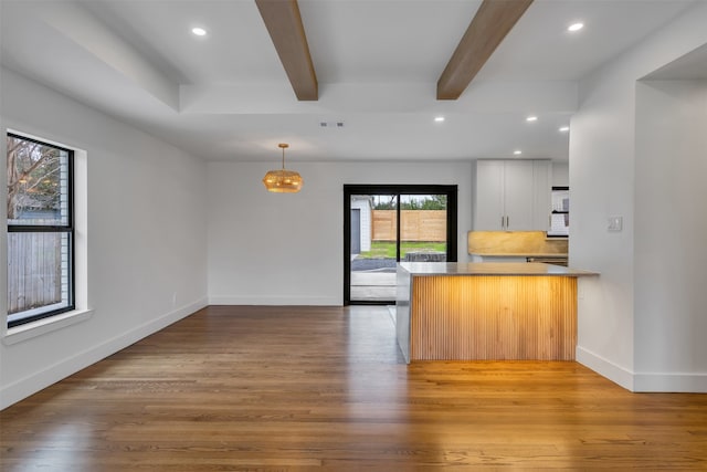 kitchen featuring a peninsula, beamed ceiling, light wood-style flooring, and baseboards