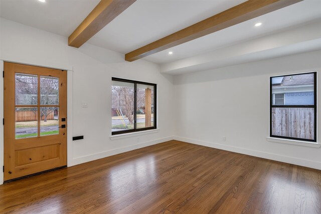 empty room with a wealth of natural light, beam ceiling, baseboards, and wood finished floors