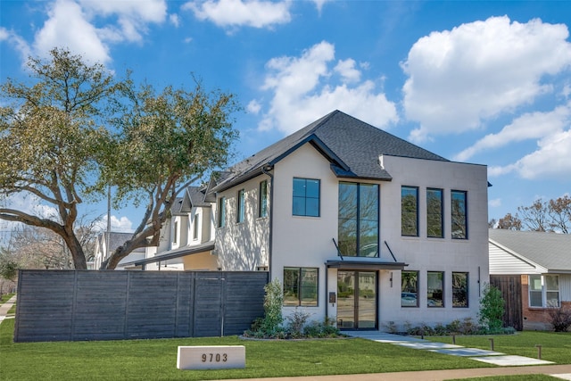 contemporary home featuring a shingled roof, fence, and a front yard