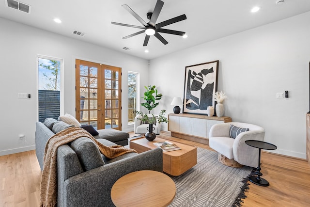 living room featuring french doors, plenty of natural light, wood finished floors, and visible vents