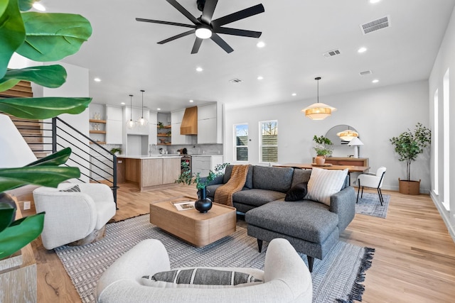 living room with light wood-type flooring, stairs, visible vents, and recessed lighting