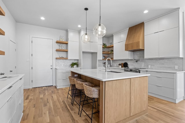 kitchen featuring a sink, stainless steel range with electric cooktop, open shelves, modern cabinets, and custom range hood