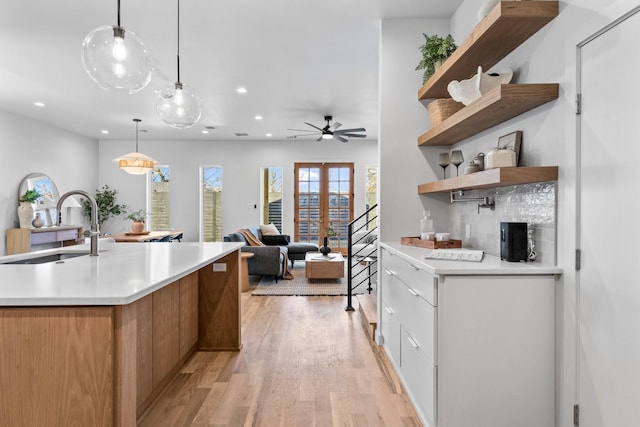 kitchen with recessed lighting, a sink, light countertops, light wood-type flooring, and open shelves