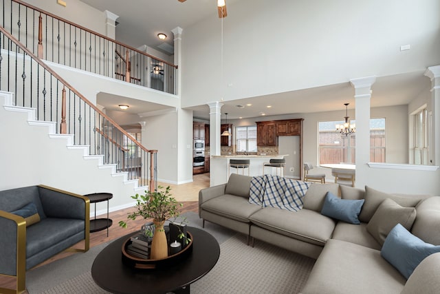 living room with decorative columns, stairs, baseboards, and a notable chandelier