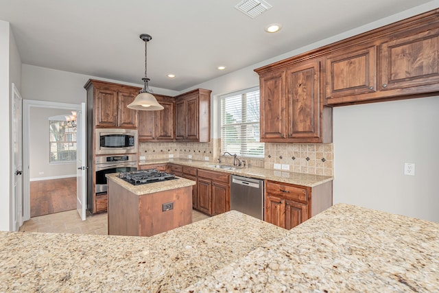 kitchen with stainless steel appliances, a sink, visible vents, light stone countertops, and tasteful backsplash