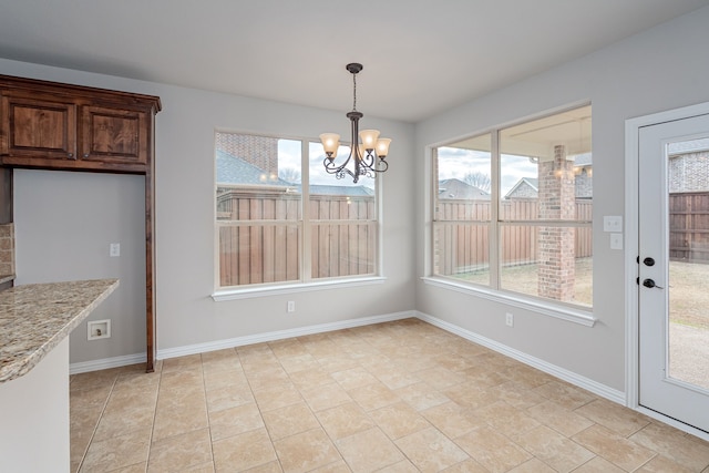 unfurnished dining area featuring an inviting chandelier and baseboards