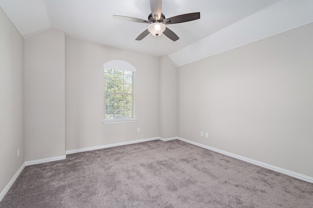 empty room with lofted ceiling, ceiling fan, carpet flooring, and baseboards