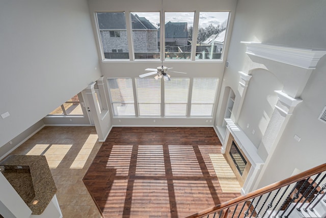 living area featuring baseboards, ceiling fan, and a high ceiling