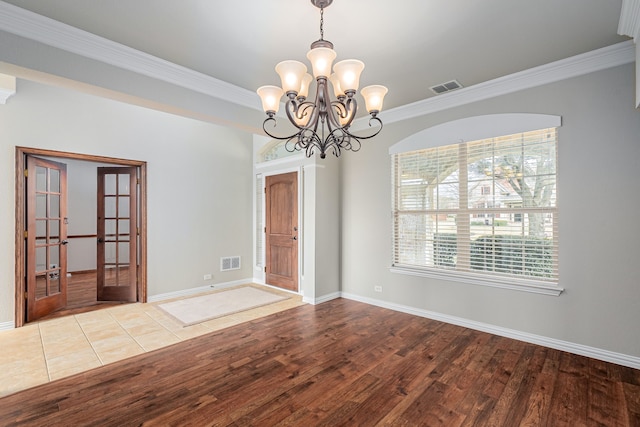 empty room with crown molding, wood finished floors, visible vents, and baseboards