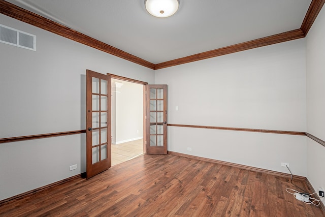 unfurnished room featuring french doors, wood-type flooring, visible vents, ornamental molding, and baseboards