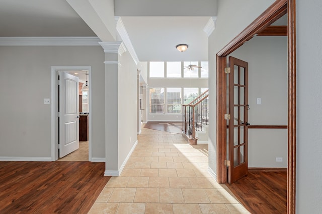 entryway with ornamental molding, decorative columns, light wood-style flooring, and stairs