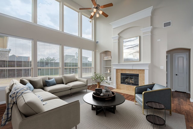 living area featuring baseboards, a tiled fireplace, wood finished floors, and built in features