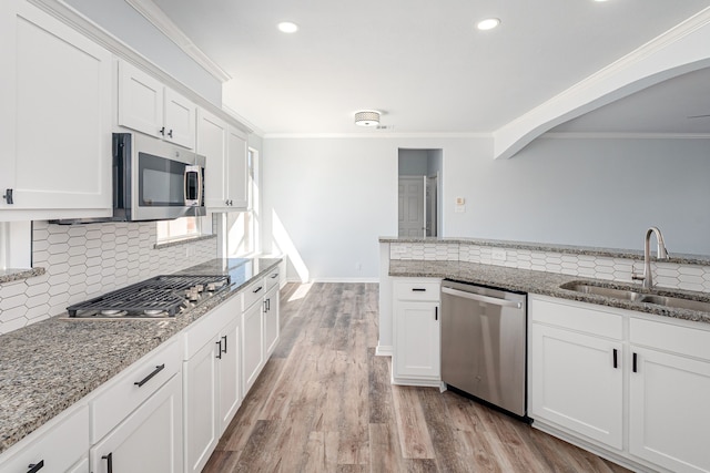 kitchen with a sink, light wood-style floors, stainless steel appliances, and crown molding