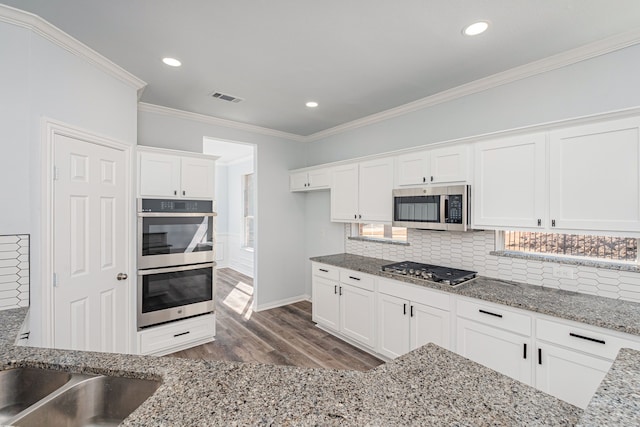 kitchen featuring crown molding, visible vents, decorative backsplash, appliances with stainless steel finishes, and white cabinets