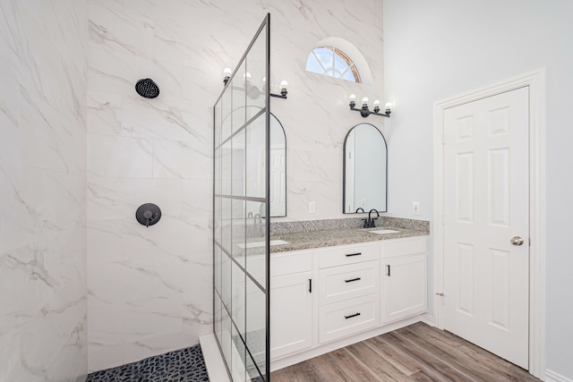 full bath with a sink, a marble finish shower, and wood finished floors